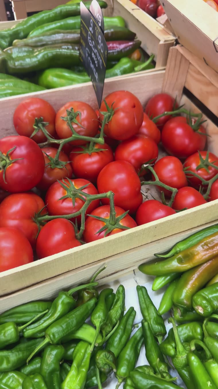 Cageots de tomates grappe et de piments verts sur l'étal.