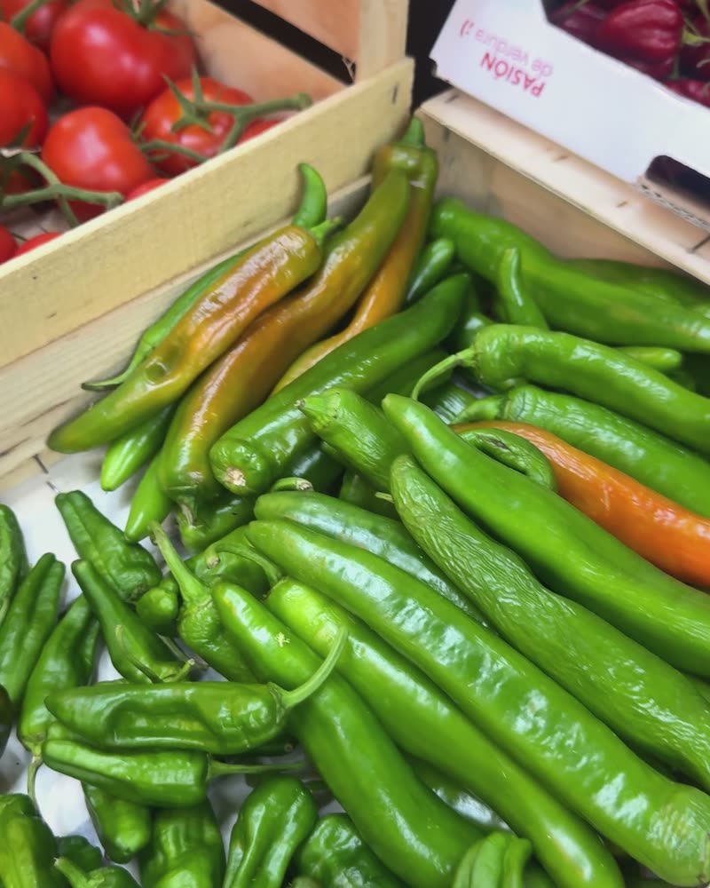 Cageot de piments verts allongés, quelques-uns virant à l'orange.